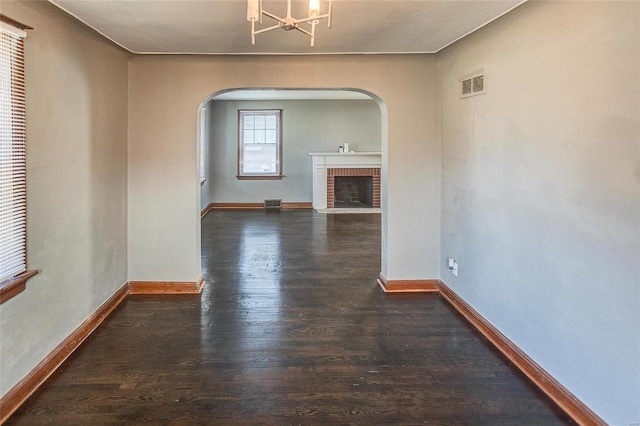 unfurnished living room featuring dark wood-style floors, arched walkways, visible vents, and baseboards