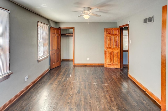 unfurnished bedroom with dark wood-style flooring, a closet, visible vents, ceiling fan, and baseboards