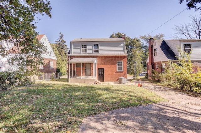 rear view of house featuring brick siding, a lawn, fence, and central air condition unit