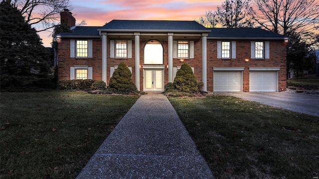 view of front of property featuring a lawn, french doors, and a garage