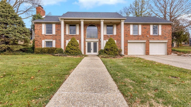 neoclassical / greek revival house with french doors, a front yard, and a garage