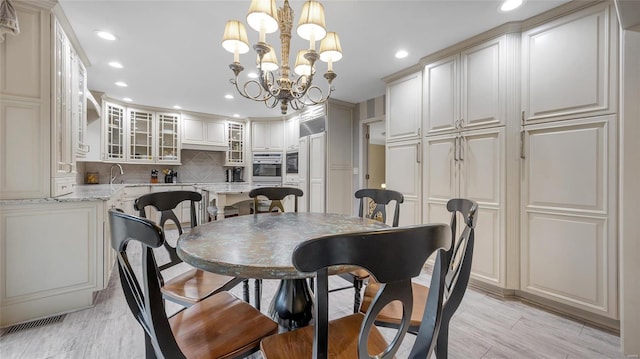 dining space featuring sink, light hardwood / wood-style flooring, and an inviting chandelier