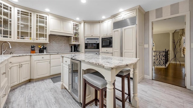 kitchen featuring light stone countertops, decorative backsplash, decorative columns, sink, and light hardwood / wood-style floors