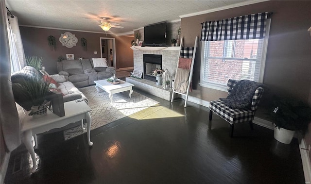 living room with ceiling fan, crown molding, a fireplace, and a textured ceiling