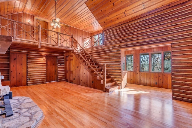 unfurnished living room with high vaulted ceiling, ceiling fan, rustic walls, wood-type flooring, and wood ceiling