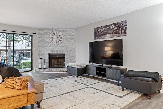 living room featuring a textured ceiling, wood-type flooring, and a fireplace