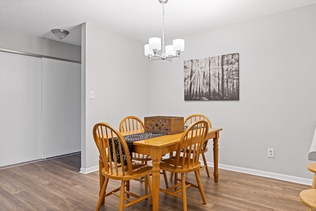 dining area with a notable chandelier, wood-type flooring, and a textured ceiling