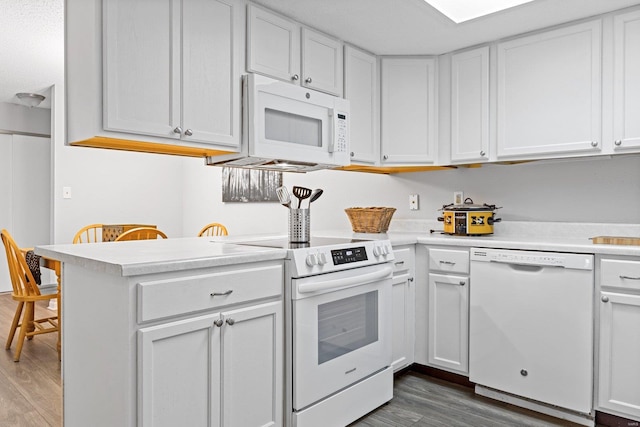 kitchen featuring kitchen peninsula, white cabinetry, dark hardwood / wood-style floors, and white appliances