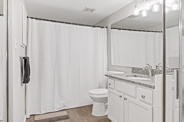 bathroom with hardwood / wood-style floors, vanity, toilet, and a textured ceiling