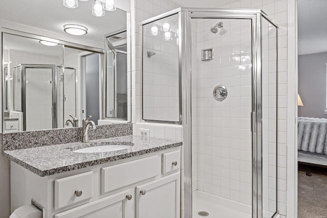 bathroom with a shower with door, vanity, and a textured ceiling