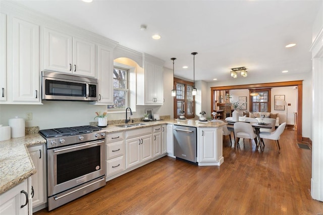 kitchen with kitchen peninsula, white cabinetry, sink, and appliances with stainless steel finishes