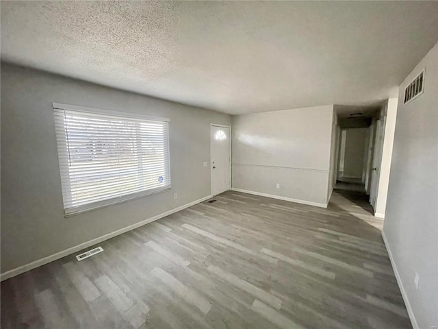 unfurnished room with wood-type flooring and a textured ceiling