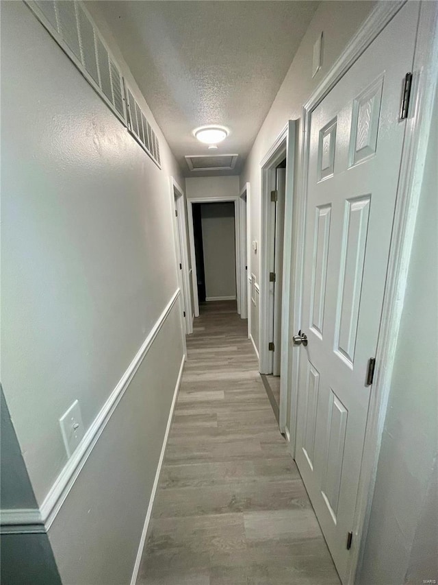 hallway featuring a textured ceiling and light hardwood / wood-style floors