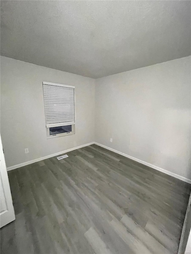 empty room featuring a textured ceiling and dark hardwood / wood-style flooring