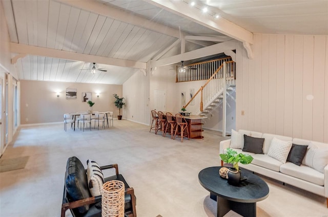 living room featuring ceiling fan, wooden walls, lofted ceiling with beams, and light carpet