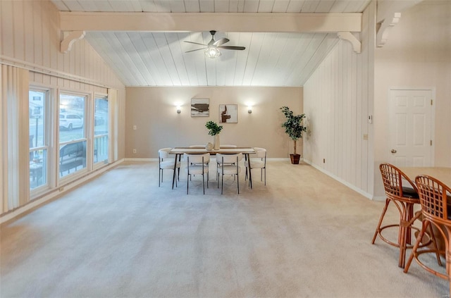 dining space featuring lofted ceiling with beams, light colored carpet, ceiling fan, and wooden walls