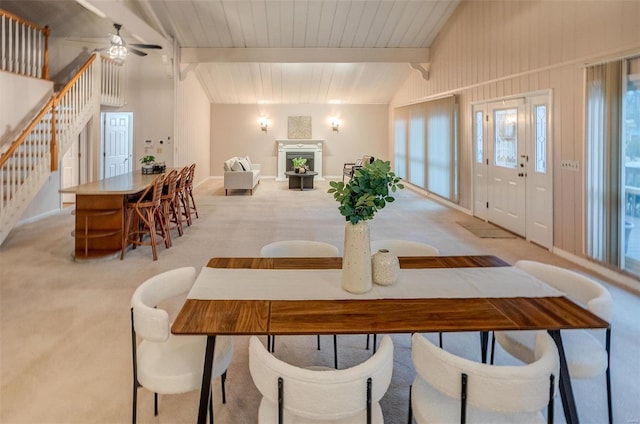 carpeted dining space with vaulted ceiling with beams and ceiling fan