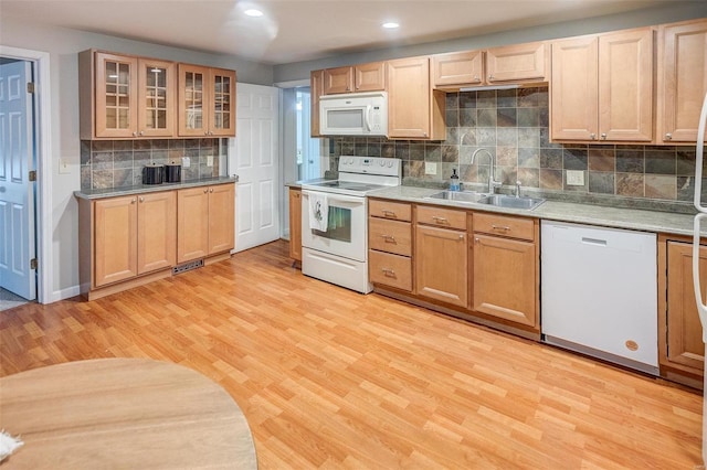 kitchen with light wood-type flooring, white appliances, sink, and tasteful backsplash