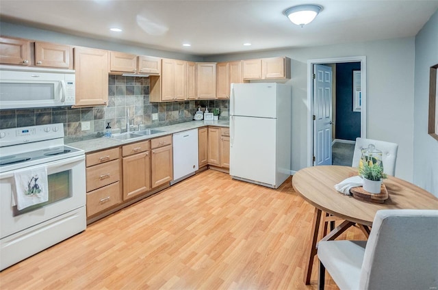 kitchen with light brown cabinetry, sink, and white appliances