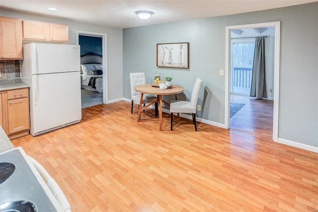 kitchen featuring backsplash, light brown cabinets, light hardwood / wood-style floors, and white refrigerator