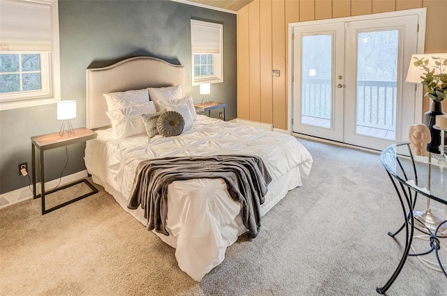 carpeted bedroom with access to outside, wood walls, and french doors