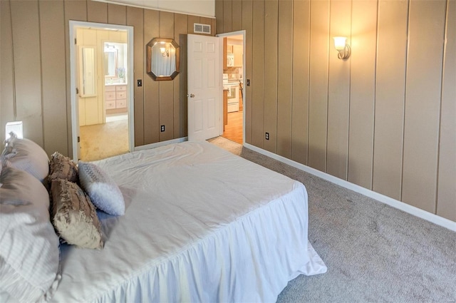 bedroom featuring ensuite bathroom, light colored carpet, and a closet