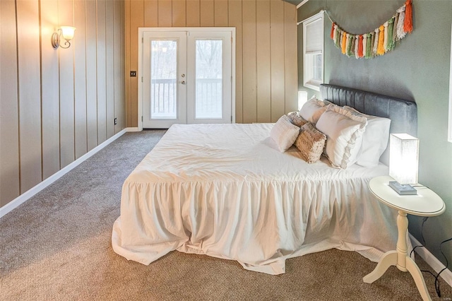 carpeted bedroom with access to outside, wood walls, and french doors