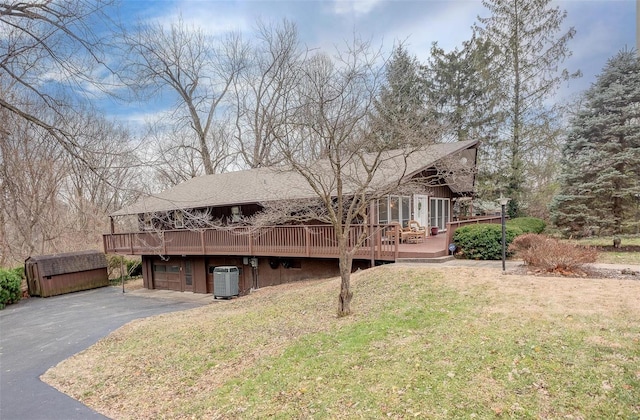 view of front of home with a sunroom, central AC, a wooden deck, a front lawn, and a garage