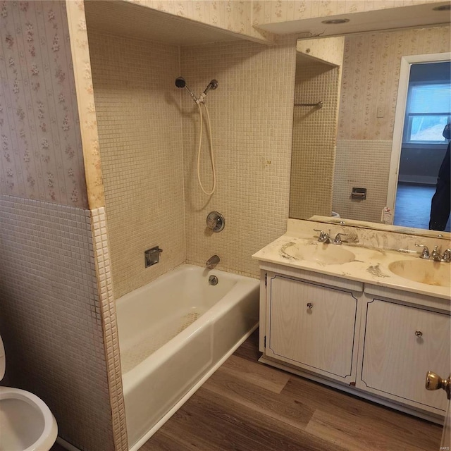 bathroom with tile walls, vanity, wood-type flooring, and tiled shower / bath combo