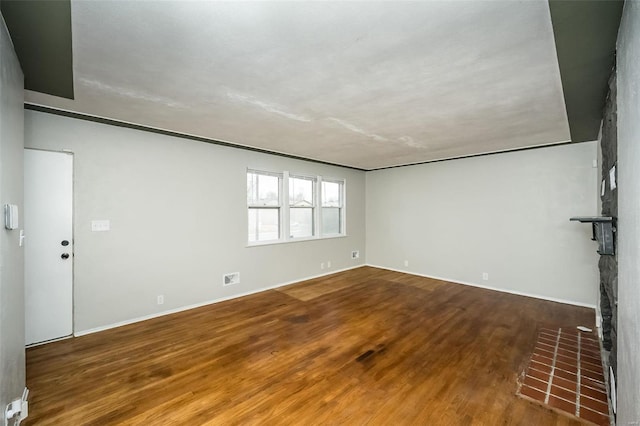 unfurnished room with wood-type flooring and a brick fireplace