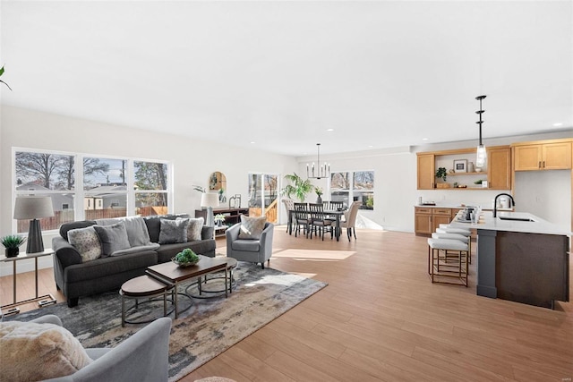 living room with a notable chandelier, light wood-type flooring, and sink