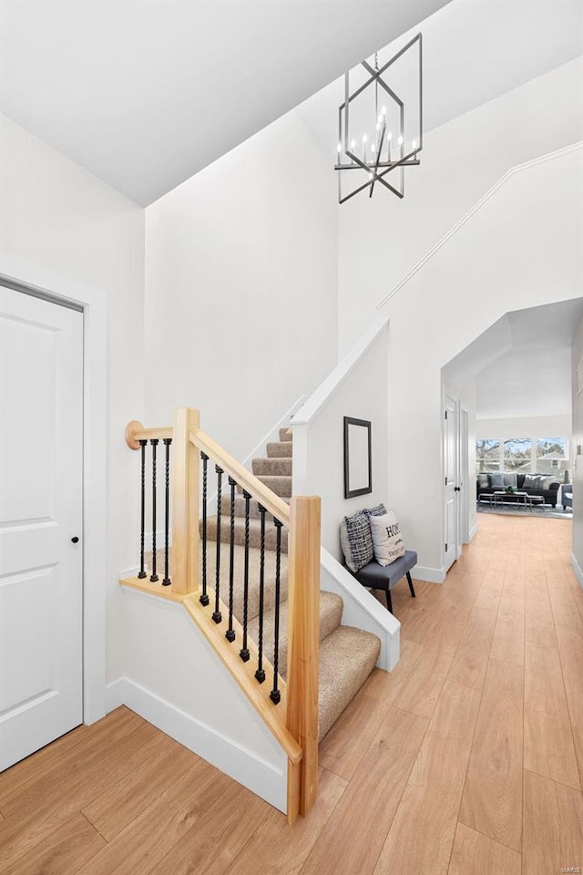 staircase with hardwood / wood-style floors and a notable chandelier