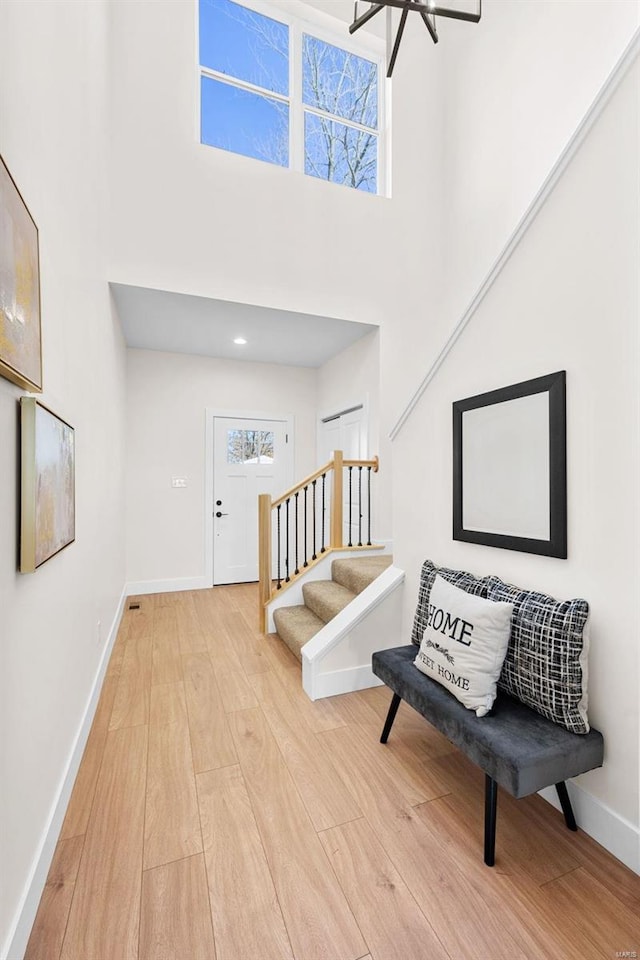 entryway with a notable chandelier, light hardwood / wood-style floors, and a high ceiling