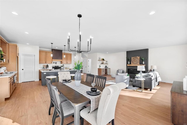 dining space featuring a chandelier, a large fireplace, and light hardwood / wood-style flooring