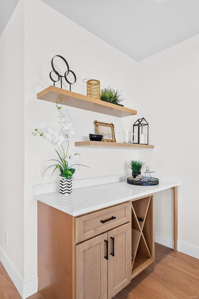 bar with light brown cabinets and light hardwood / wood-style floors