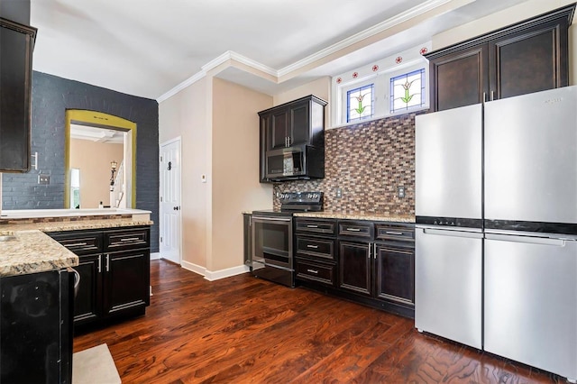 kitchen featuring appliances with stainless steel finishes, dark hardwood / wood-style flooring, backsplash, light stone counters, and crown molding