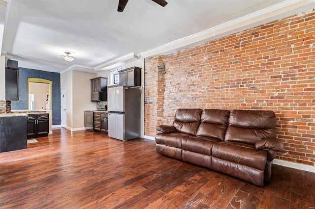 unfurnished living room with ceiling fan, brick wall, ornamental molding, and dark hardwood / wood-style floors