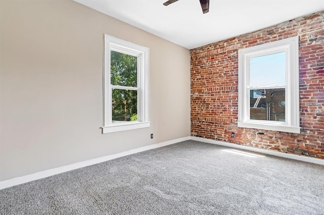 unfurnished room featuring ceiling fan, brick wall, and carpet