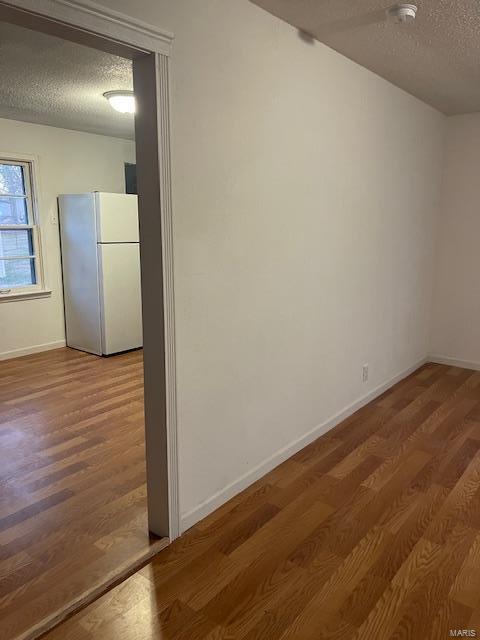 empty room with a textured ceiling and hardwood / wood-style flooring