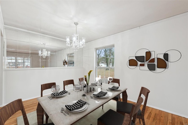 dining room featuring hardwood / wood-style flooring, ornamental molding, and an inviting chandelier