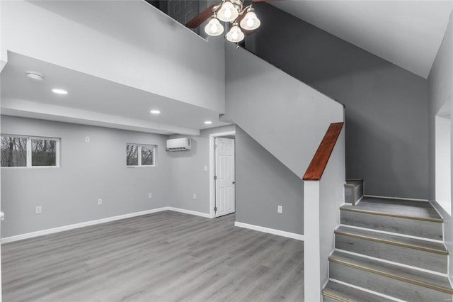 basement with a wall mounted air conditioner, ceiling fan, and light hardwood / wood-style flooring