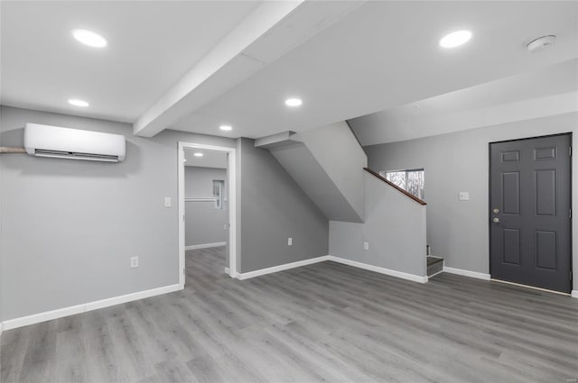 interior space with a wall mounted air conditioner and hardwood / wood-style floors