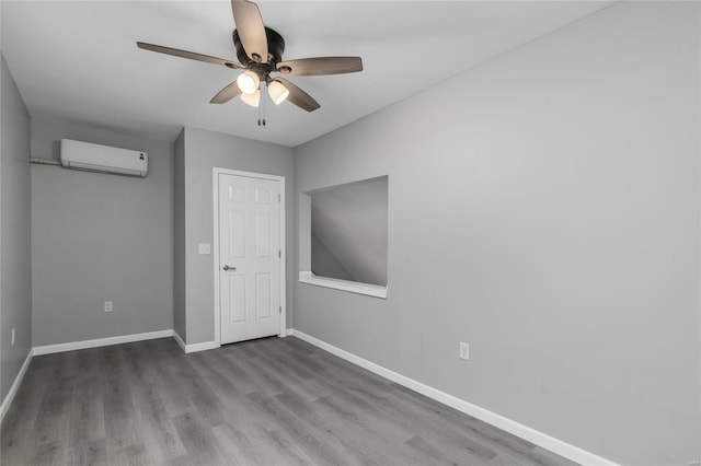 unfurnished bedroom featuring a wall mounted air conditioner, wood-type flooring, and ceiling fan