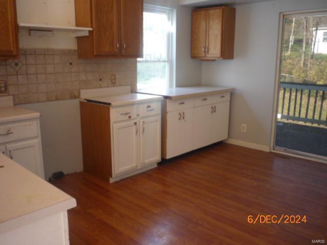 kitchen with backsplash, white cabinets, and dark wood-type flooring