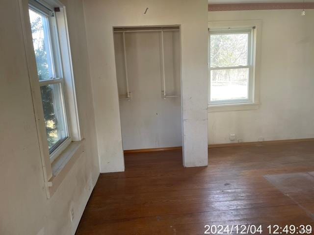 unfurnished bedroom featuring a closet, dark hardwood / wood-style floors, and multiple windows