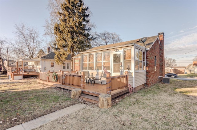 rear view of property featuring a sunroom and a deck