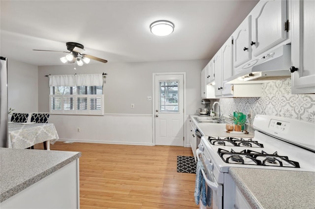 kitchen featuring white cabinetry, sink, ceiling fan, light hardwood / wood-style floors, and white range with gas cooktop