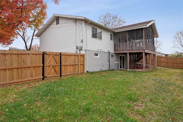 rear view of house featuring a sunroom, central AC unit, and a lawn