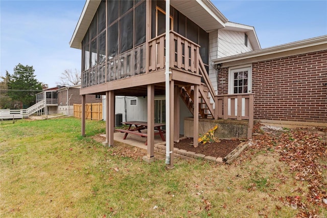 rear view of property with central AC unit, a lawn, a patio area, and a sunroom