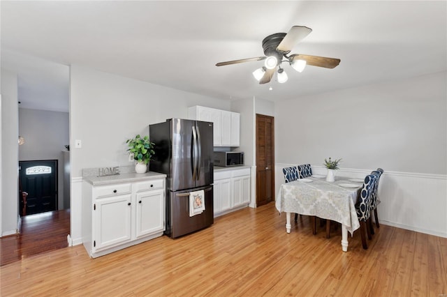 kitchen with white cabinets, stainless steel fridge, light hardwood / wood-style flooring, and ceiling fan